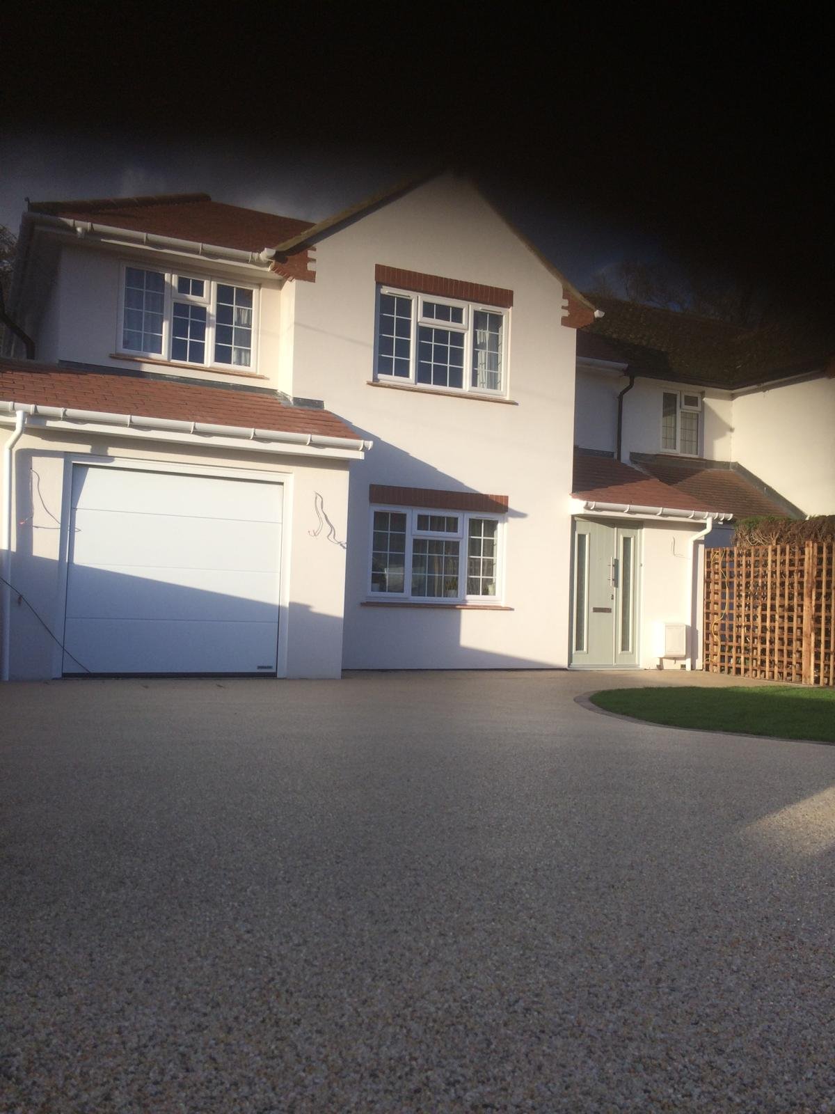 Dark surfaced driveway in front of a cream house with a double garage