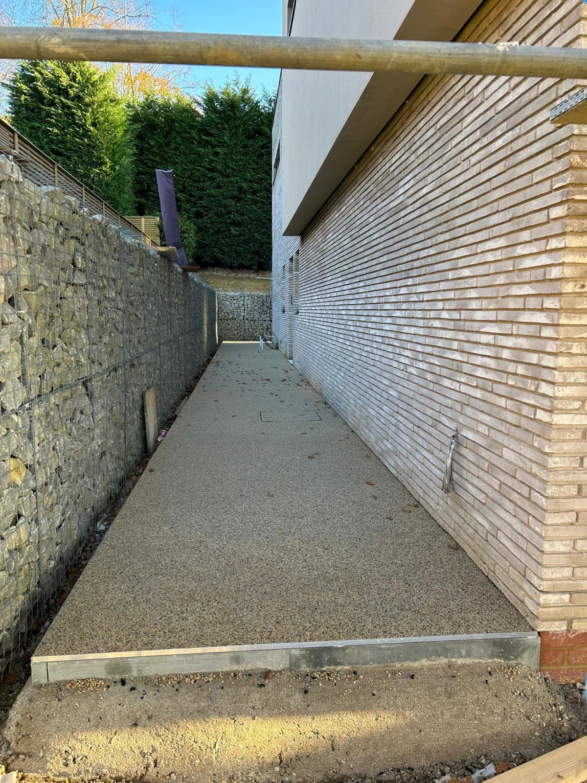 Golden resin bound side path between brick and stone walls